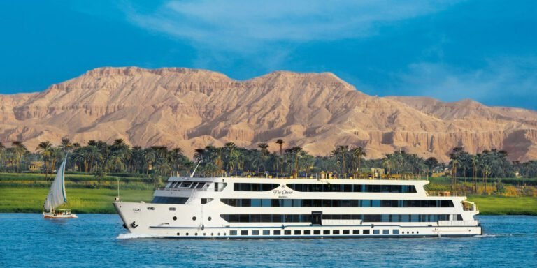 Nile cruise ship passing palm groves and a felucca