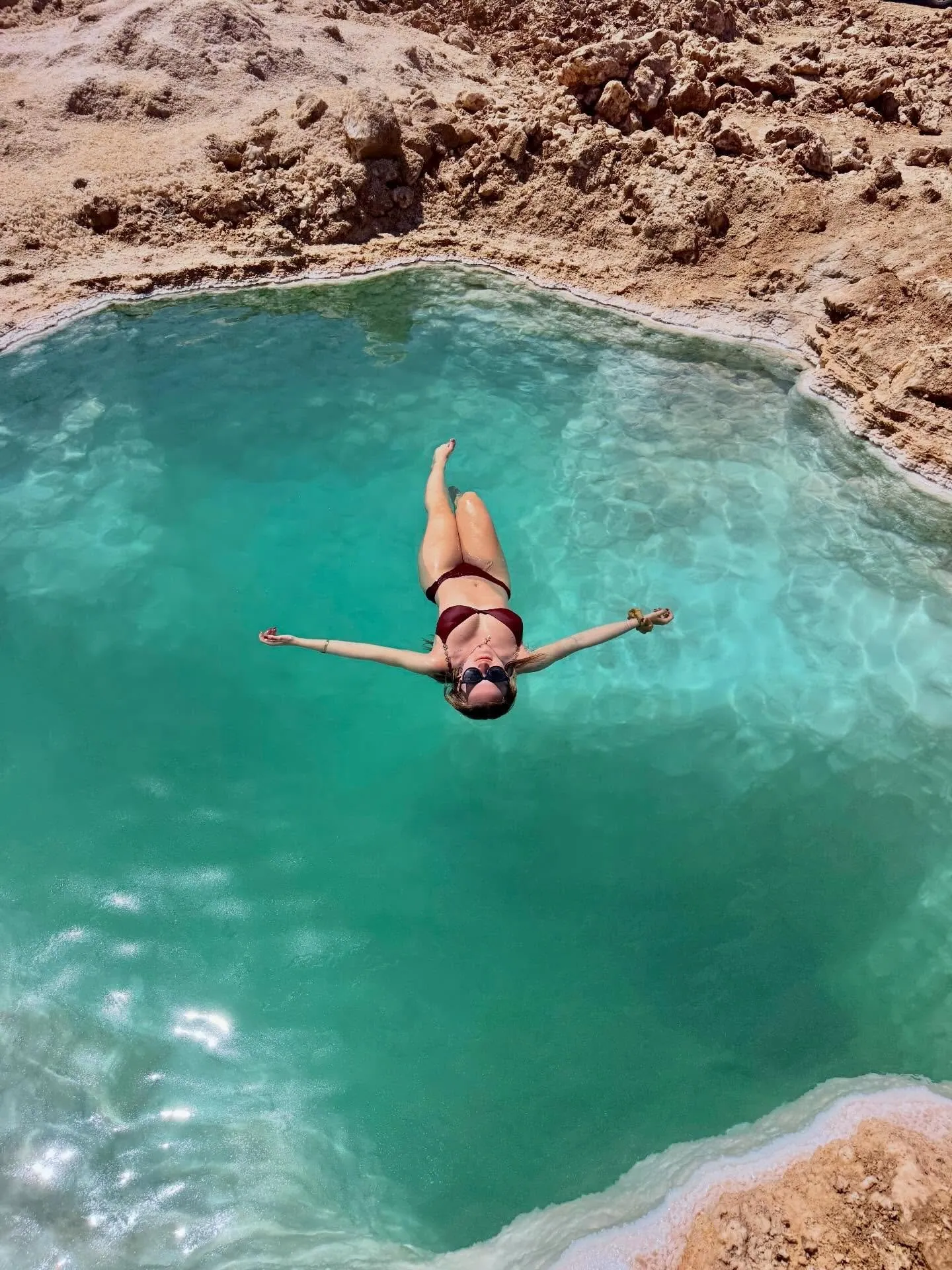 A traveller floating in a turquoise natural salt pool in the Egyptian desert
